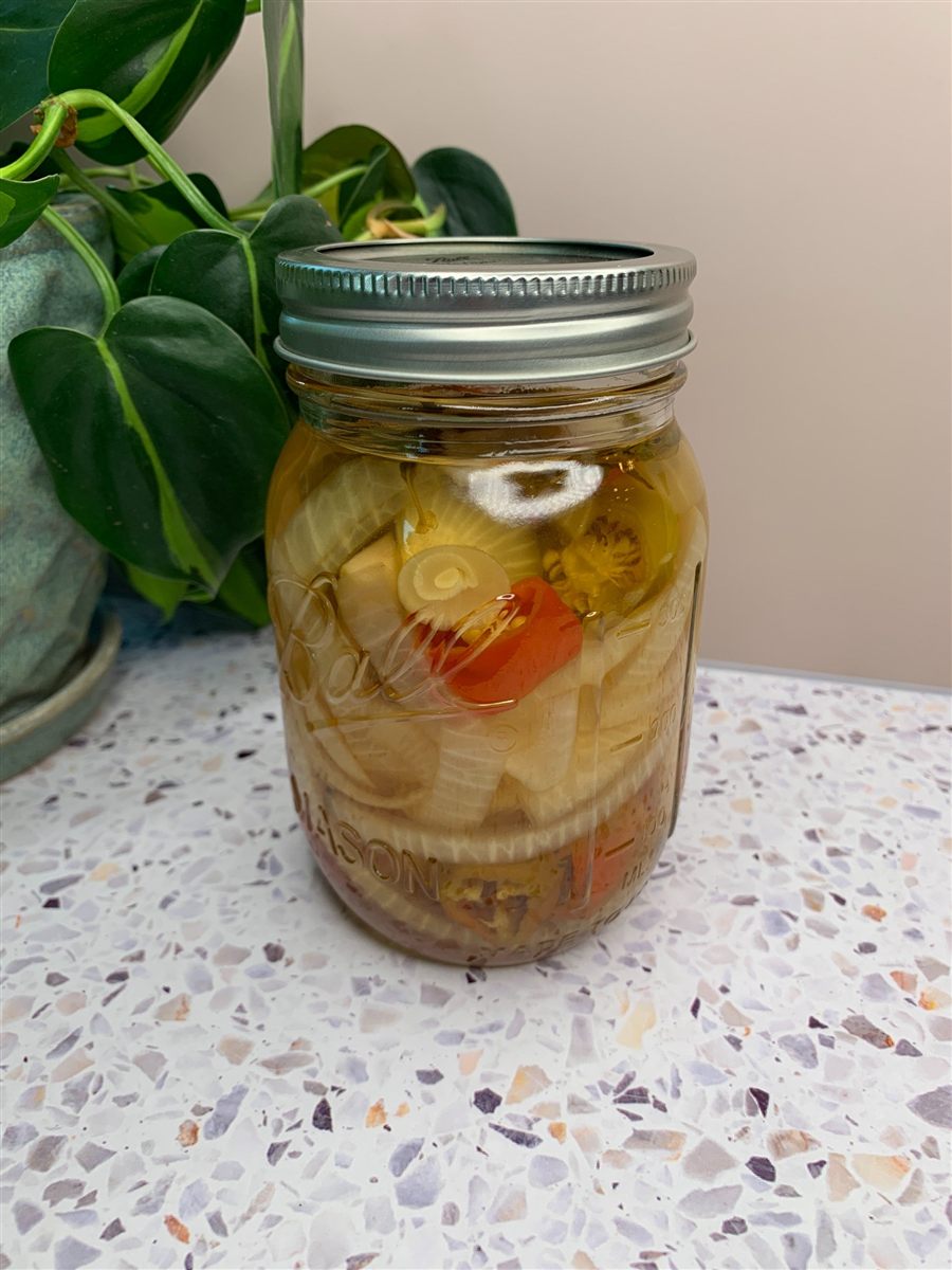 A jar of pickled peppers and onions.