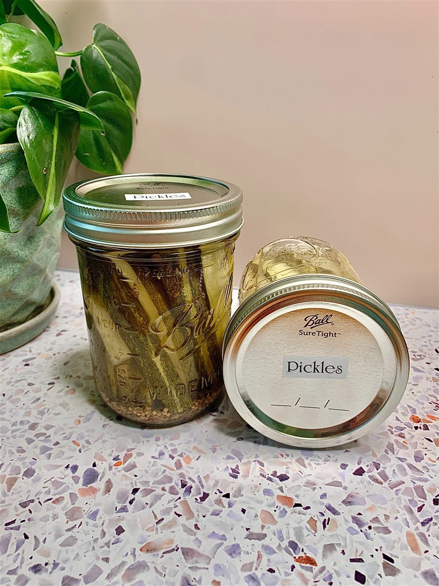 Two jars of homemade pickles labelled by hand.
